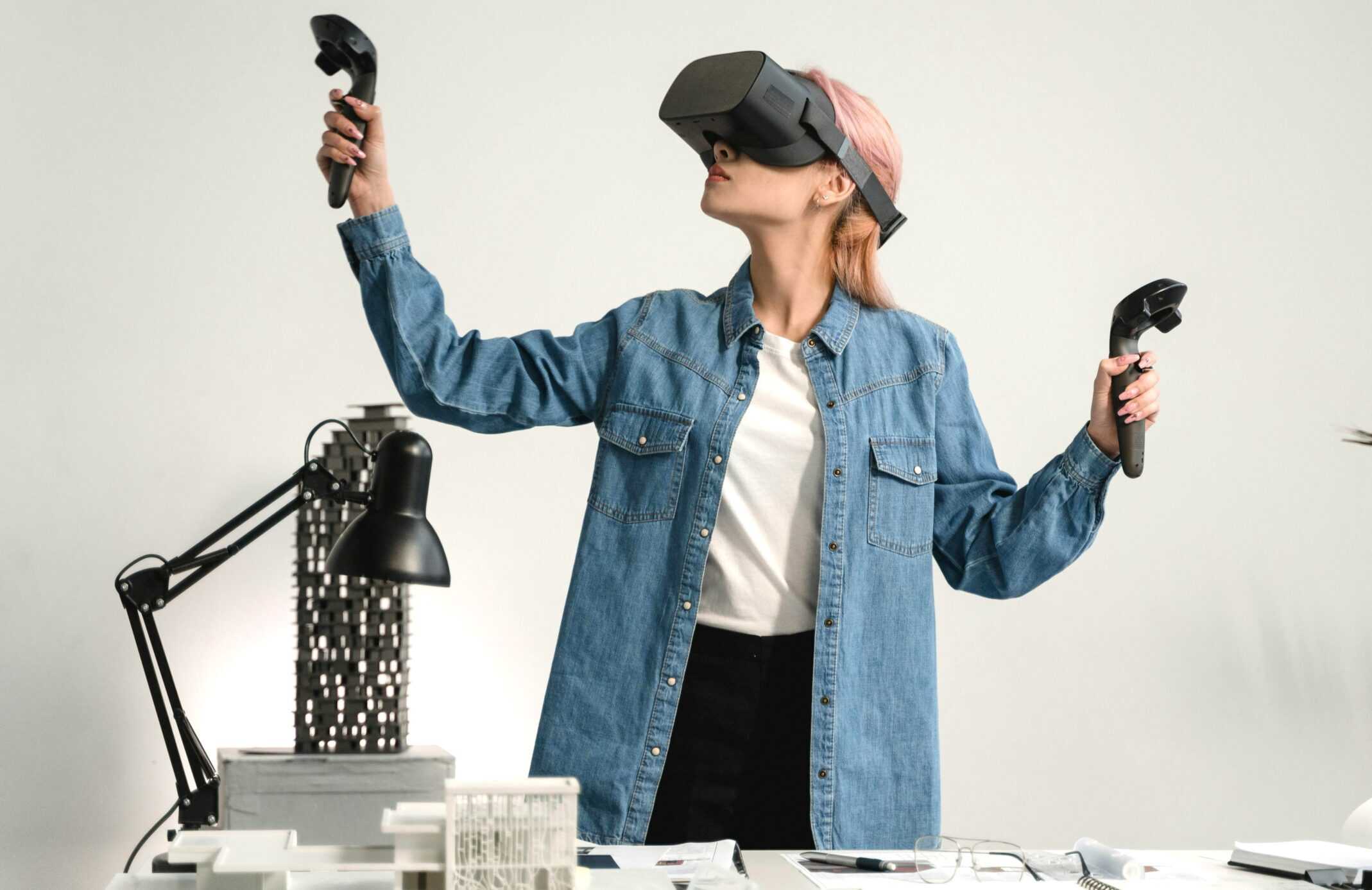 Woman in blue denim jacket working at a desk using a VR system, virtual reality, future, futuristic