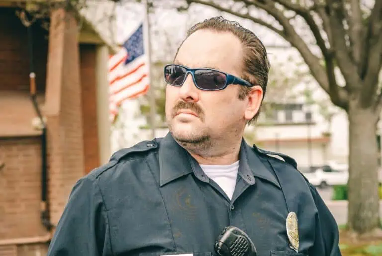 Man in Police Uniform Standing on the Street in front of American flag
