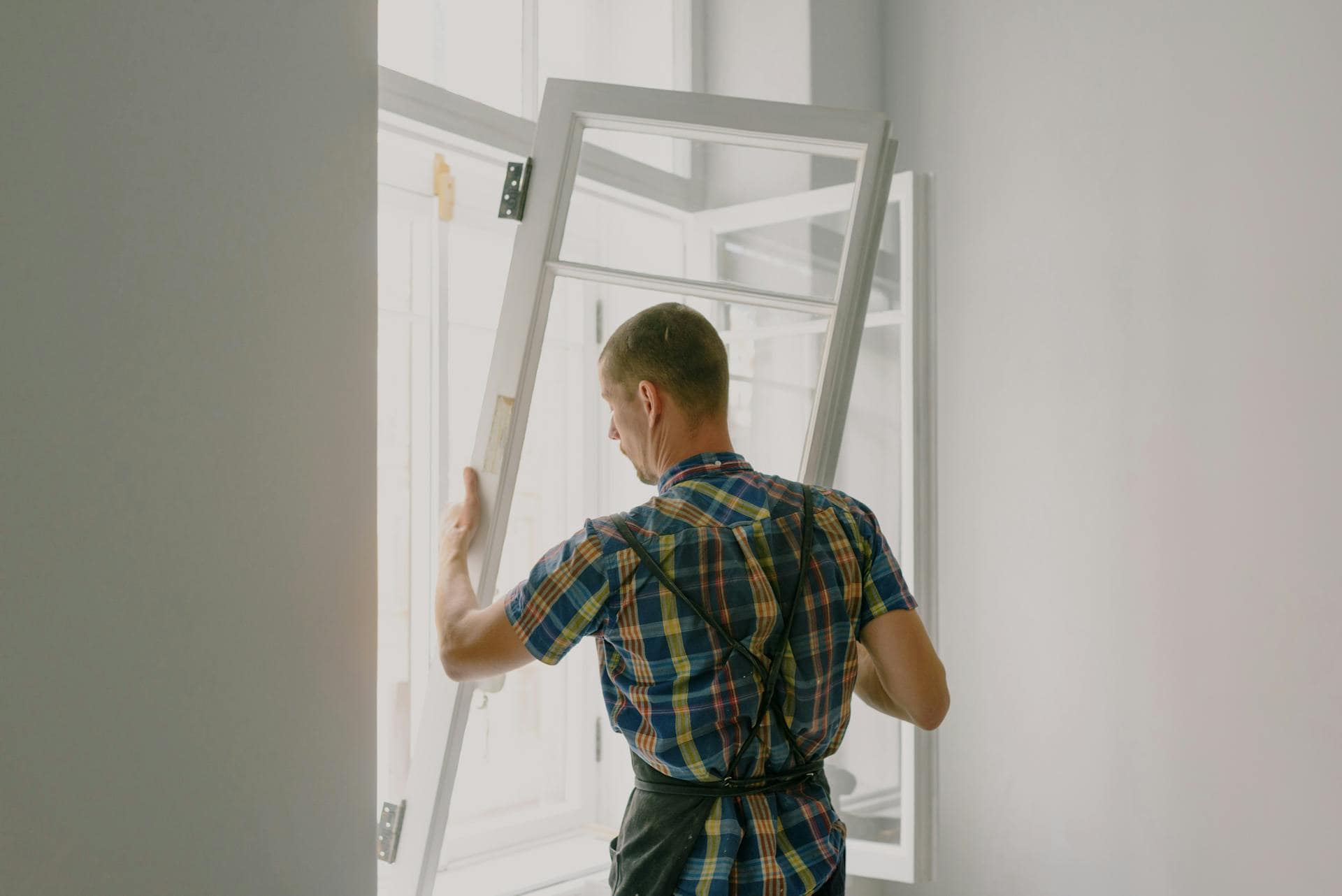 workman installing window in house during renovation process
