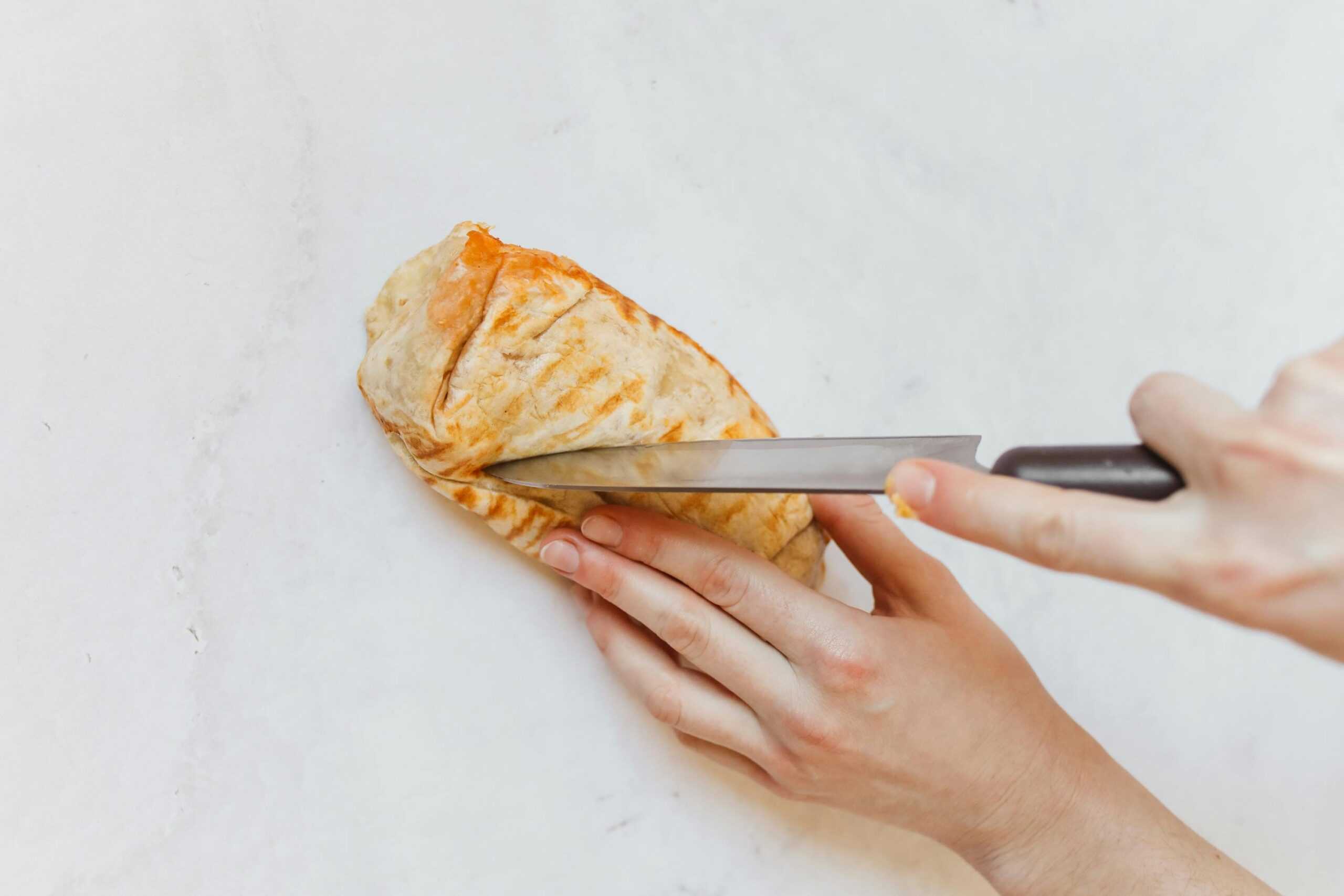 Person cutting loaded burrito with a knife