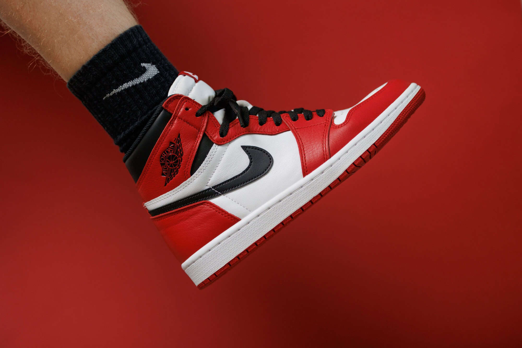 DRESDEN, GERMANY - Aug 14, 2022: A Men wearing Nike Air Jordan 1 Sneakers with black socks isolated on the red background