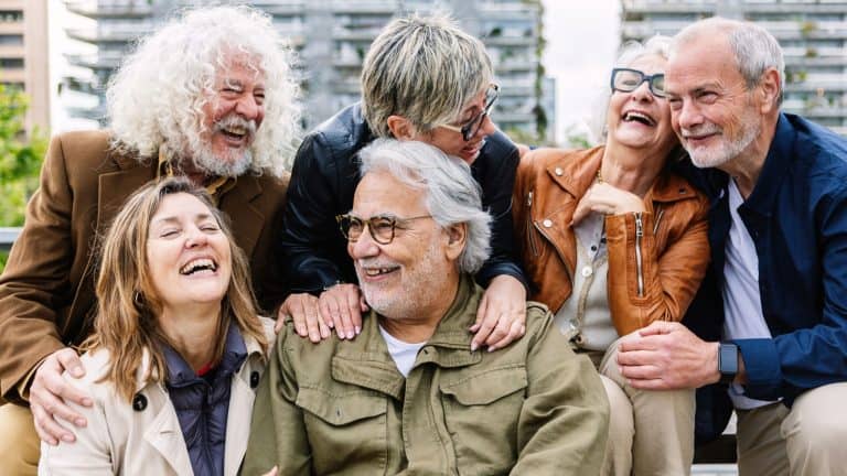 Happy group of senior people laughing while sitting together outdoors. Elderly mature people
