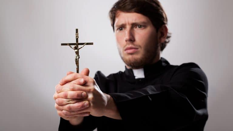 Young christian priest is holding a cross