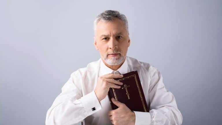Old man looking at camera and holding Bible