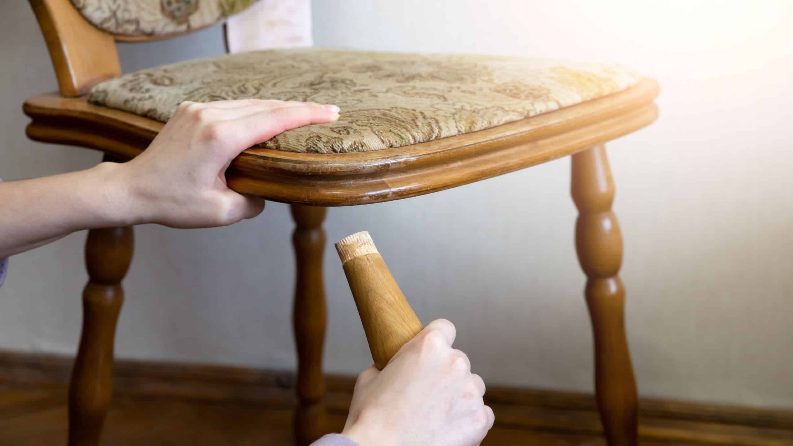 Broken chair. Woman is holding it in hands. Old furniture.