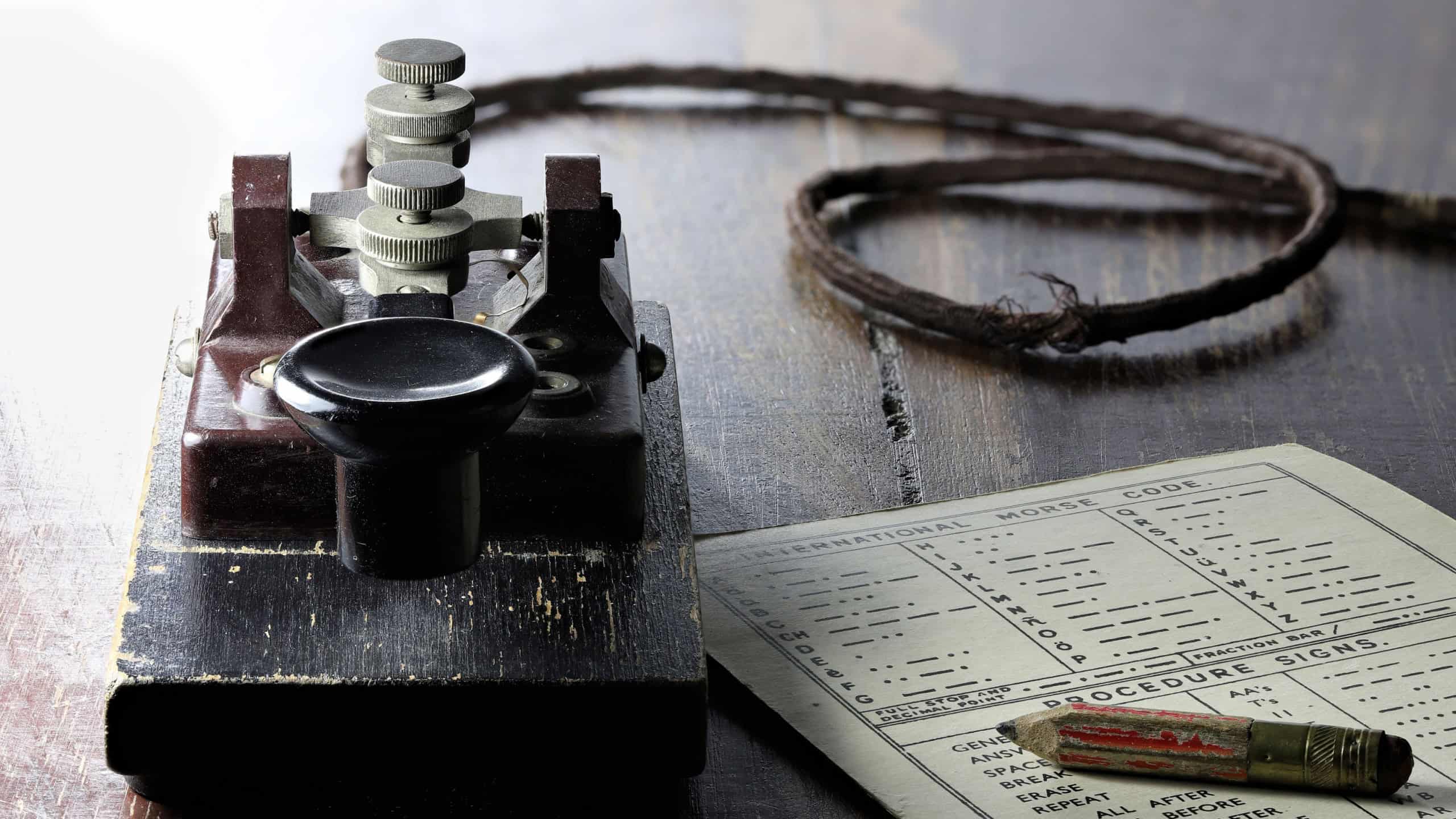 morse key with morse code chart on desk