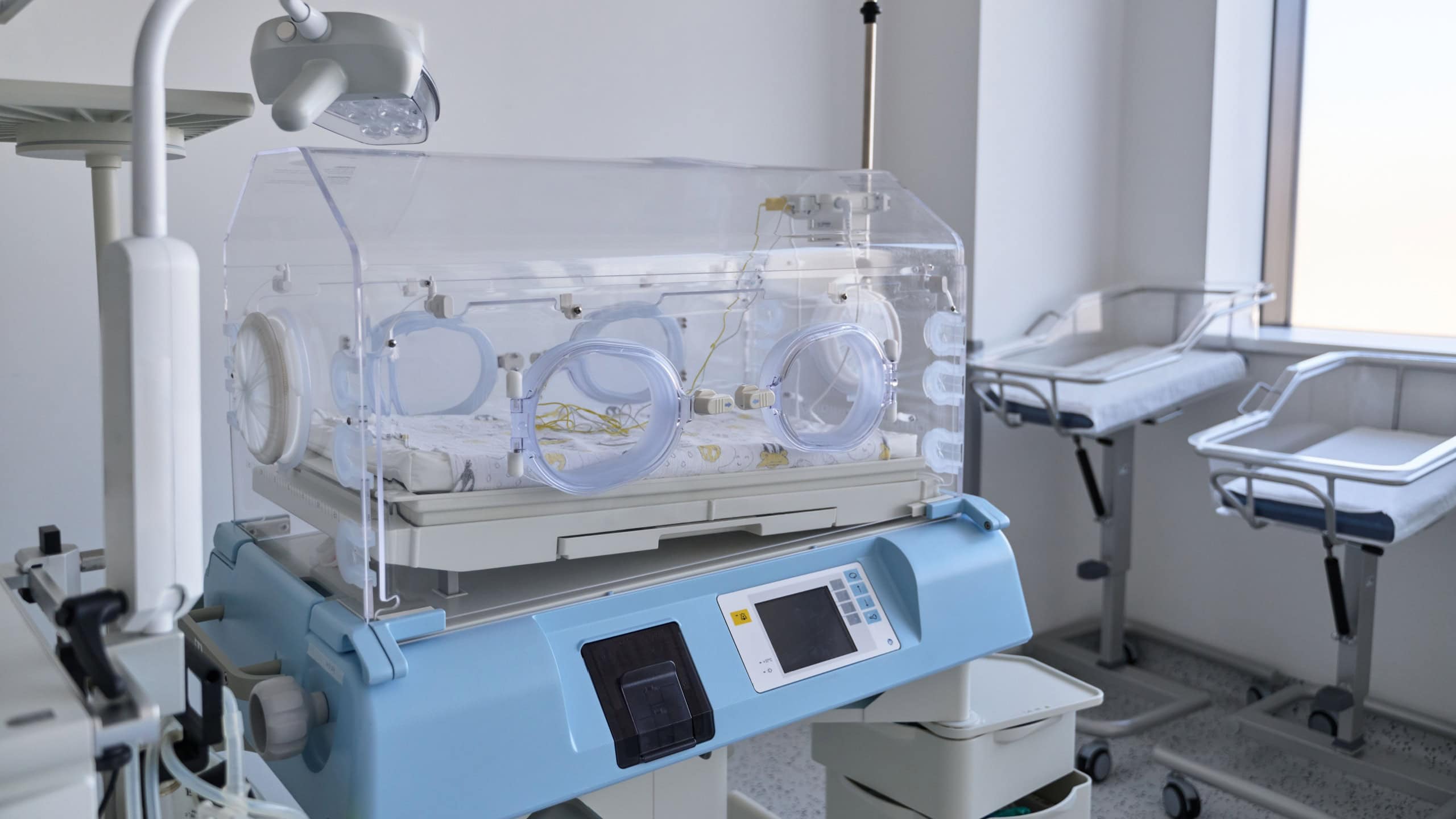 Advanced neonatal incubator in a bright, clean hospital room during daytime