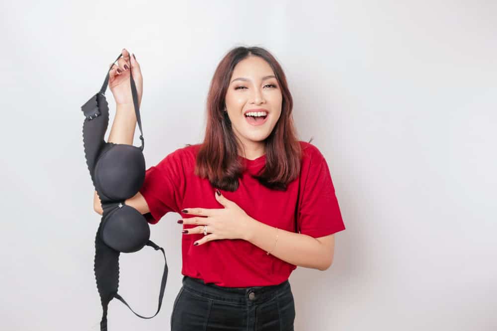 a smiling woman holding up a black bra
