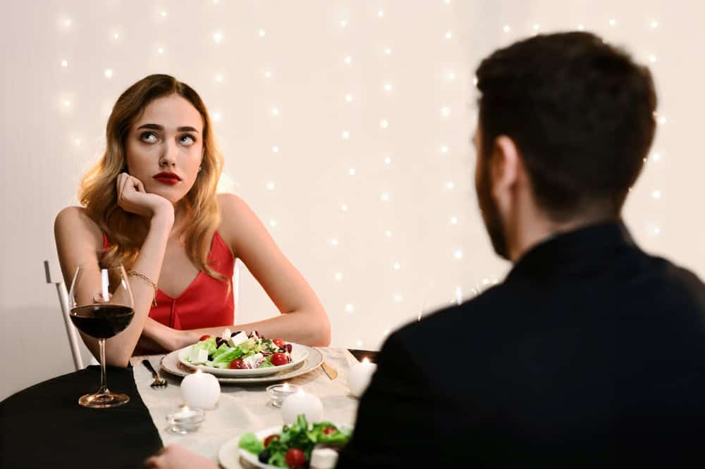 Unsuccessful Date. Young woman feeling bored at dinner in restaurant, looking away with disappointed